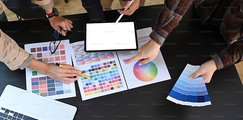 People working on a branding project with color palettes and a tablet.